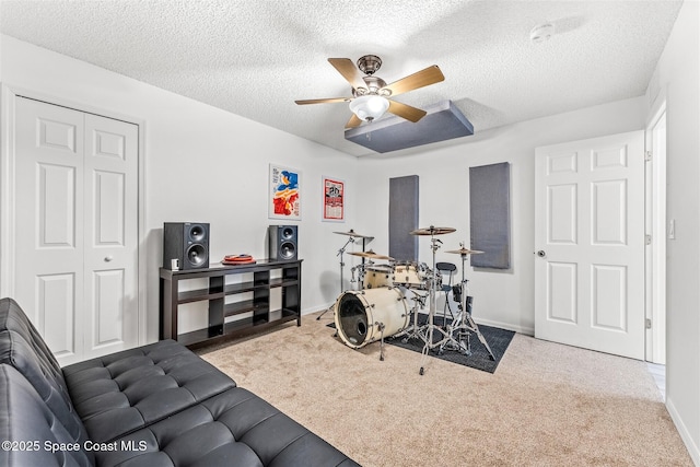 workout room featuring ceiling fan, light colored carpet, and a textured ceiling