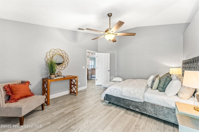 bedroom with ceiling fan, lofted ceiling, light hardwood / wood-style floors, and a textured ceiling