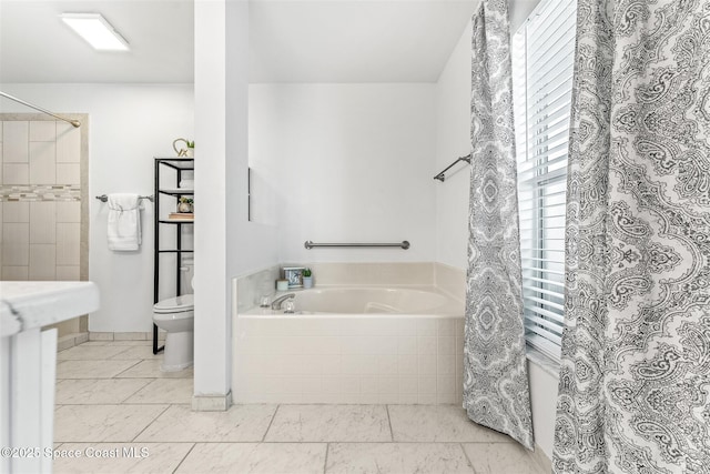 bathroom featuring toilet and tiled bath