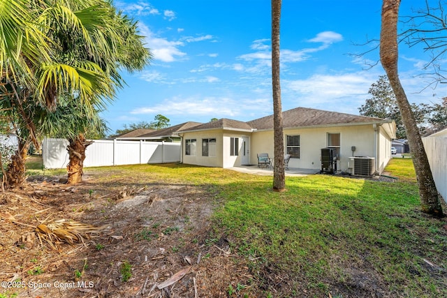 rear view of property featuring a lawn, a patio area, and central air condition unit