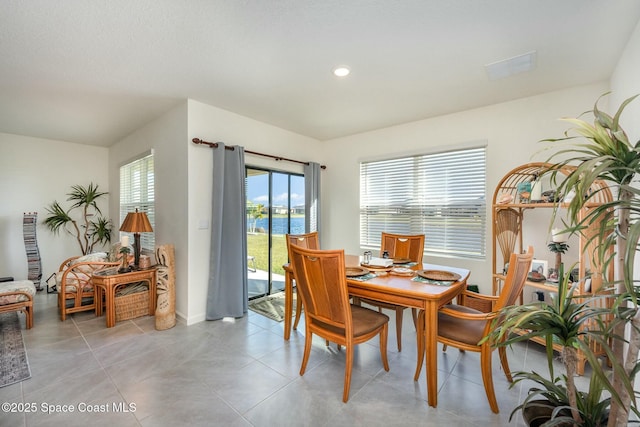 dining room with light tile patterned floors and a water view