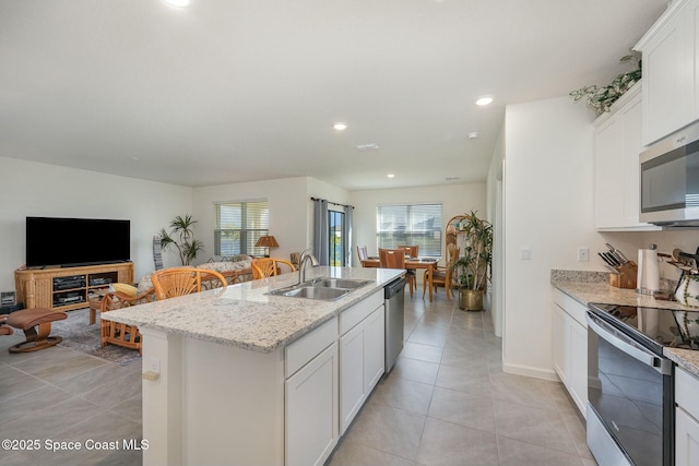 kitchen featuring white cabinetry, sink, a kitchen island with sink, stainless steel appliances, and light stone countertops