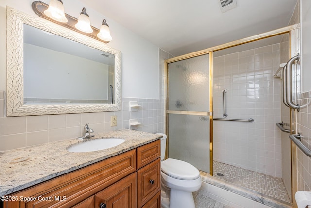 bathroom featuring an enclosed shower, vanity, tile walls, and toilet