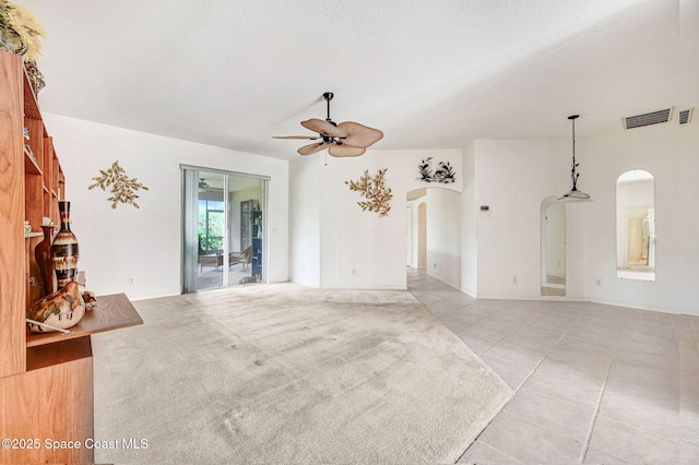 unfurnished living room featuring light carpet, a textured ceiling, and ceiling fan