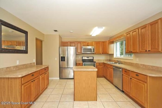 kitchen with light tile patterned flooring, appliances with stainless steel finishes, a center island, and kitchen peninsula