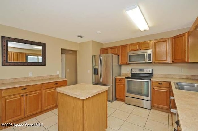 kitchen featuring stainless steel appliances, sink, a center island, and light tile patterned floors