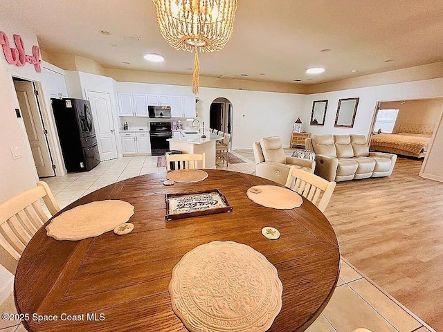 dining area with sink, light tile patterned floors, and a chandelier