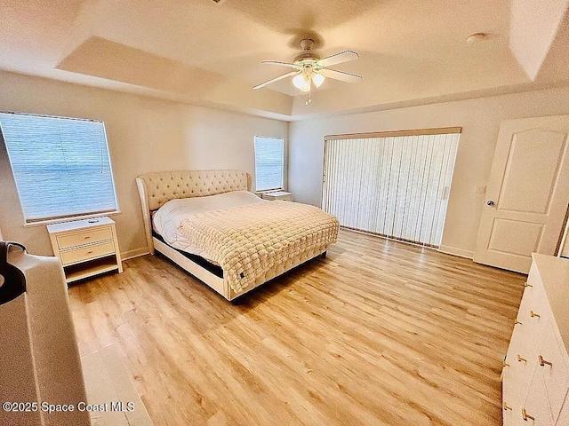 bedroom with a tray ceiling, light hardwood / wood-style flooring, and ceiling fan