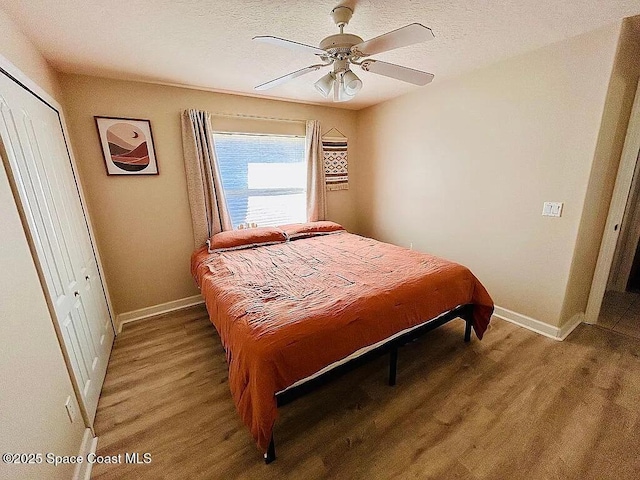 bedroom featuring hardwood / wood-style flooring, a textured ceiling, a closet, and ceiling fan