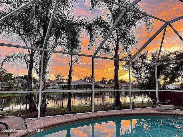 pool at dusk with a water view and a lanai