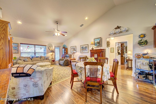 dining room with ceiling fan, high vaulted ceiling, and light wood-type flooring