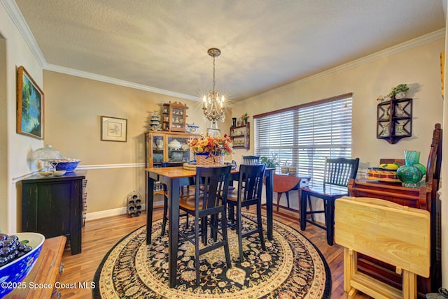 dining space with hardwood / wood-style flooring, ornamental molding, a chandelier, and a textured ceiling