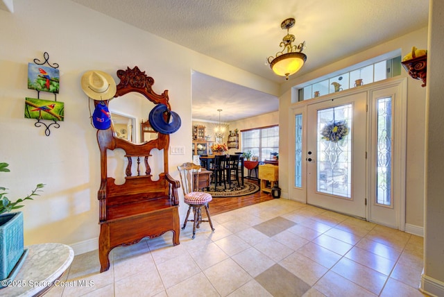 foyer entrance with light tile patterned flooring, a textured ceiling, and a notable chandelier