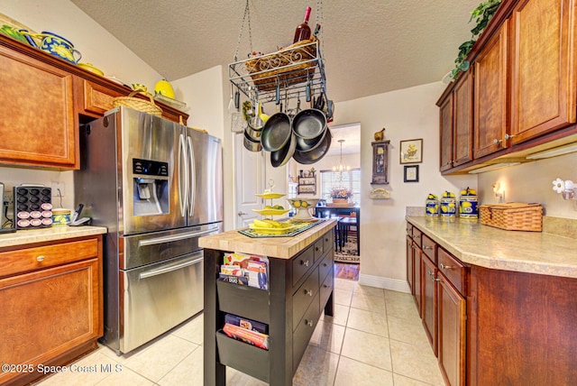 kitchen featuring light tile patterned floors, a textured ceiling, and stainless steel refrigerator with ice dispenser