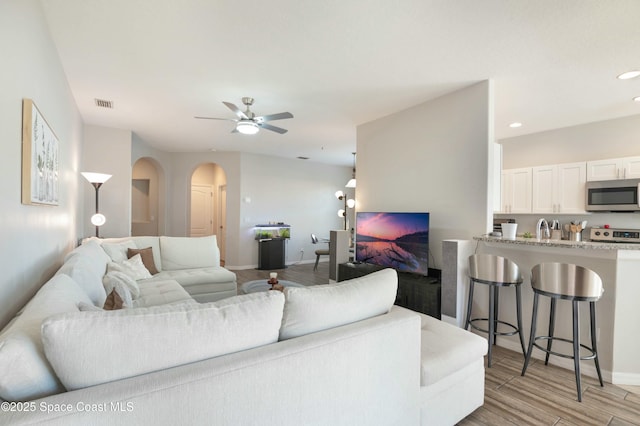 living room featuring sink, light hardwood / wood-style floors, and ceiling fan