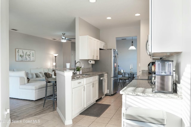 kitchen featuring white cabinetry, sink, light stone counters, and appliances with stainless steel finishes