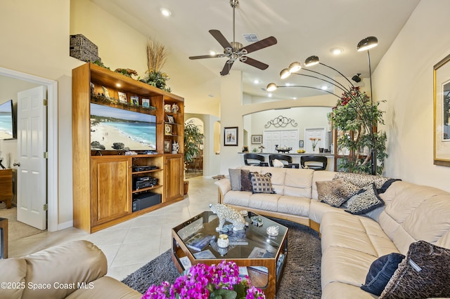 tiled living room with ceiling fan and high vaulted ceiling