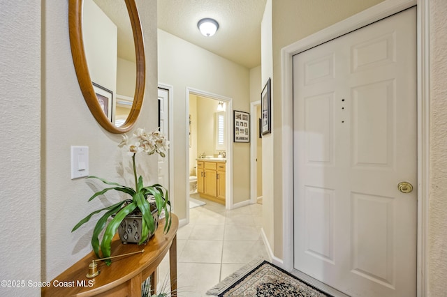 corridor featuring a textured ceiling and light tile patterned floors