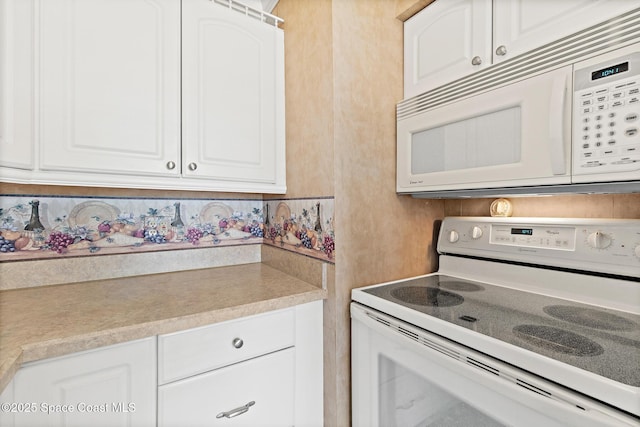 kitchen with white appliances, white cabinets, and light countertops