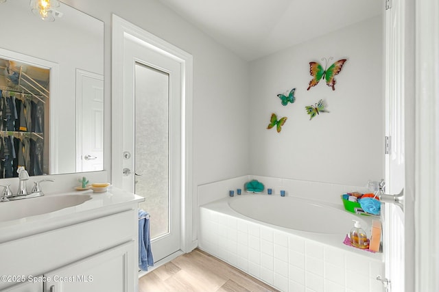 bathroom with vanity, wood-type flooring, and tiled bath