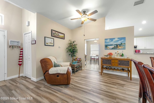 sitting room with ceiling fan, high vaulted ceiling, and light wood-type flooring