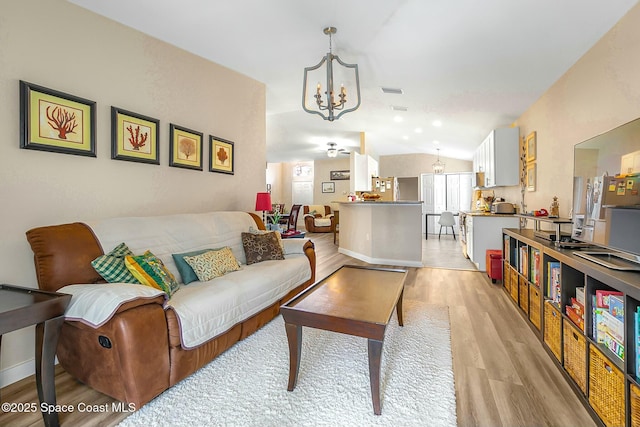 living room with lofted ceiling, a chandelier, light hardwood / wood-style flooring, and a wealth of natural light