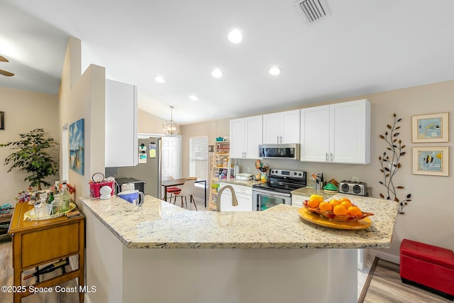 kitchen featuring lofted ceiling, hanging light fixtures, kitchen peninsula, stainless steel appliances, and white cabinets