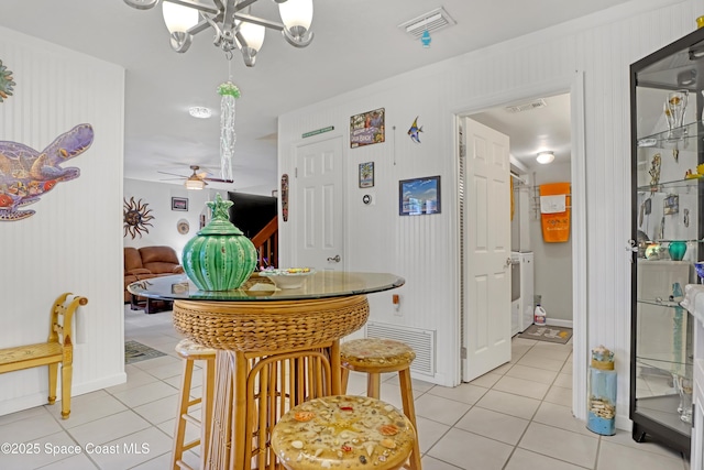 dining space featuring light tile patterned flooring and ceiling fan with notable chandelier