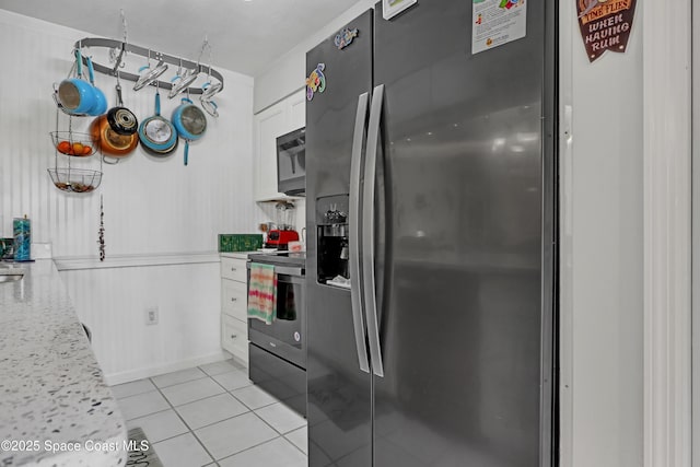 kitchen featuring light stone counters, stainless steel appliances, white cabinets, and light tile patterned flooring