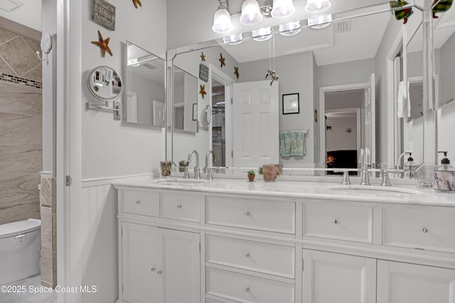 bathroom with vanity, toilet, and a tile shower