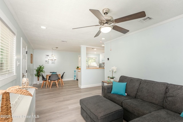 living room featuring ceiling fan with notable chandelier, light hardwood / wood-style flooring, and ornamental molding