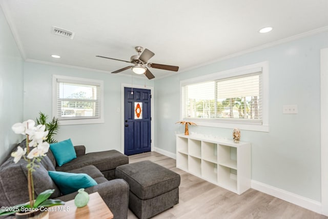 living room featuring crown molding, ceiling fan, and light wood-type flooring