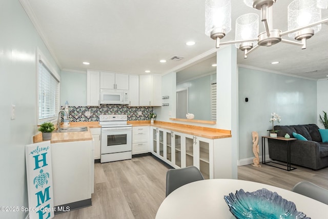 kitchen with sink, white appliances, tasteful backsplash, white cabinets, and wood counters