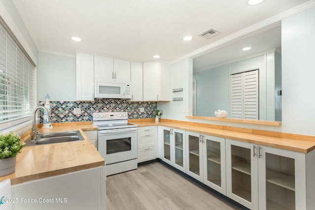 kitchen featuring white cabinets, sink, wooden counters, and white appliances