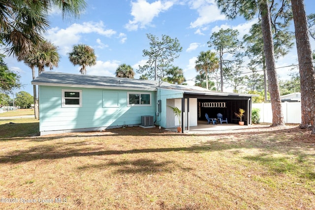 rear view of house featuring a garage, a yard, and central AC unit