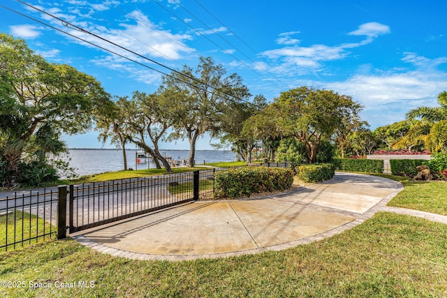 surrounding community with a water view and a yard