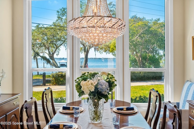 dining room featuring a water view, plenty of natural light, and a chandelier