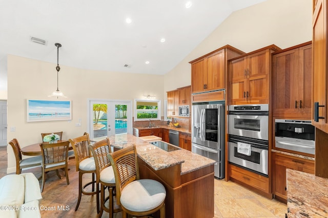 kitchen featuring appliances with stainless steel finishes, decorative light fixtures, sink, light stone counters, and french doors