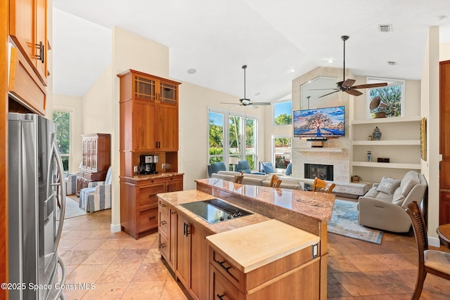 kitchen with black electric cooktop, stainless steel fridge, a center island, and a healthy amount of sunlight