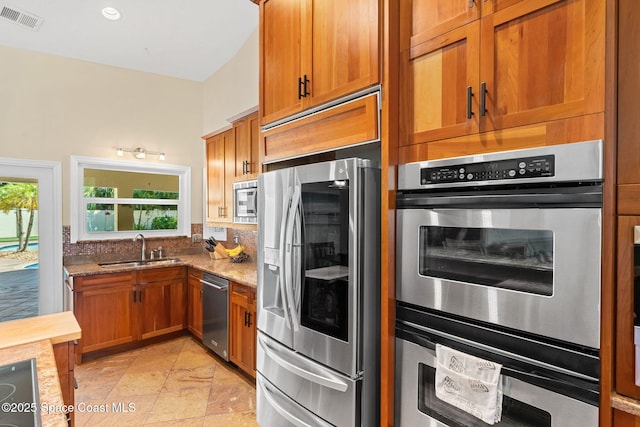 kitchen with light stone counters, sink, plenty of natural light, and appliances with stainless steel finishes