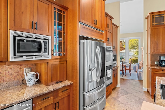 kitchen with light stone countertops, appliances with stainless steel finishes, light tile patterned floors, and decorative backsplash