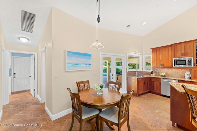 dining space with sink, a towering ceiling, and french doors