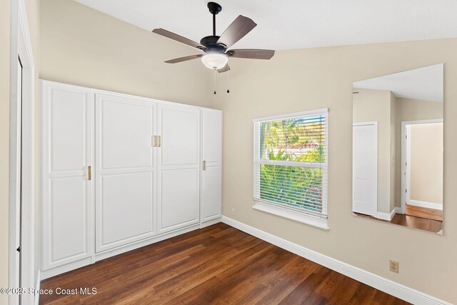 unfurnished bedroom featuring lofted ceiling, a closet, dark hardwood / wood-style floors, and ceiling fan