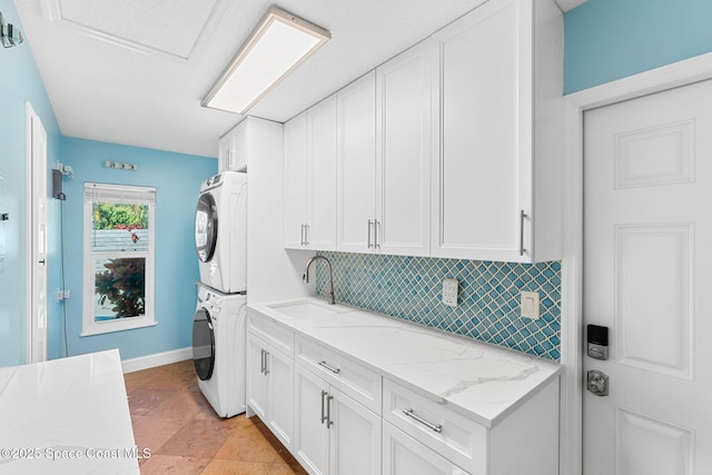 laundry room with cabinets, stacked washer and clothes dryer, and sink