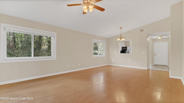 spare room with lofted ceiling, ceiling fan with notable chandelier, and light wood-type flooring