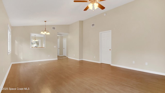 unfurnished room featuring hardwood / wood-style flooring, lofted ceiling, and ceiling fan with notable chandelier