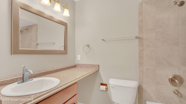 full bathroom featuring tiled shower / bath, vanity, and toilet