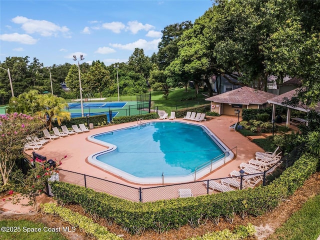 view of swimming pool featuring tennis court