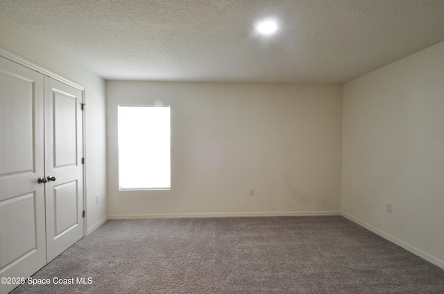 empty room with carpet floors and a textured ceiling