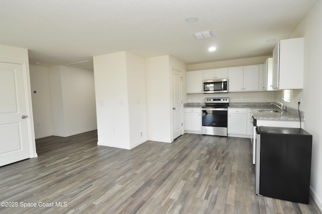 kitchen featuring sink, white cabinets, stainless steel appliances, light stone countertops, and dark wood-type flooring